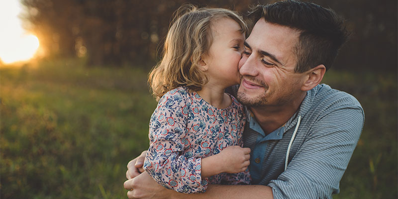 father being kissed on cheek by young daughter